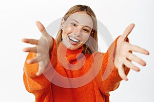 Portrait of beautiful blond girl smiling, reaching hands forward, stretching arms to hold, receive smth, hugging gesture