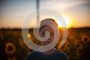 Portrait of beautiful blond kid boy on summer sunflower field