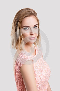Portrait of beautiful blond sensual woman in pink cocktail dress on grey background