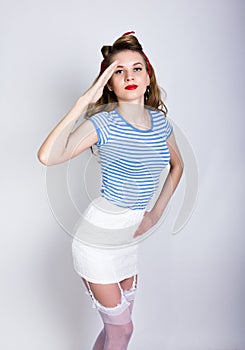 Portrait of a beautiful blond in a striped shirt, white skirt and lacy stockings, sailor saluting with a Yes Sir. Pin Up