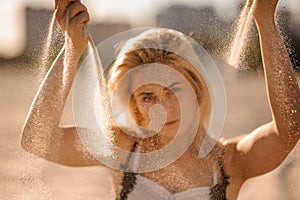 Portrait of beautiful blond woman with sand