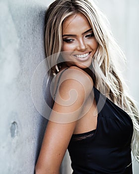 Portrait of beautiful blond young woman in a classic black dress elegant clothes