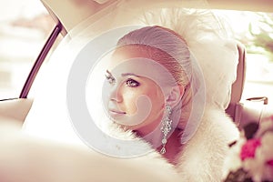 Portrait of beautiful blonde bride sitting in the wedding car