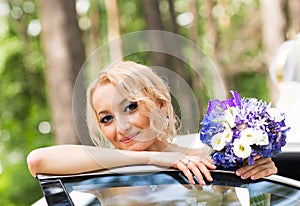 Portrait of a beautiful blonde bride with the wedding car.