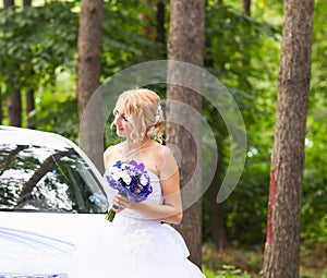 Portrait of a beautiful blonde bride with the wedding car.