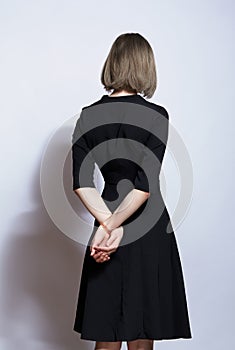 Portrait of beautiful blonde female in black dress from back side