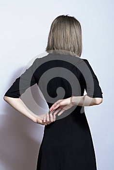 Portrait of beautiful blonde female in black dress from back side