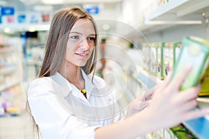 Portrait of beautiful blonde female pharmacist reading a label