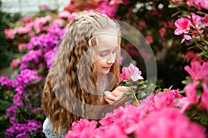 Portrait of beautiful blonde girl with flower in the park, in the greenhouse azaleas