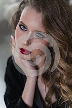 Portrait of a beautiful blonde girl with red lips and evening makeup, wavy hair wearing a black velvet jacket. Healthy, clean skin