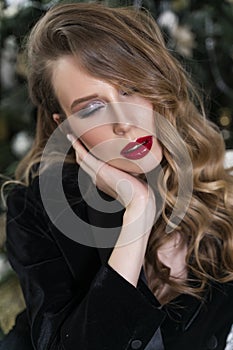 Portrait of a beautiful blonde girl with red lips and evening makeup, wavy hair wearing a black velvet jacket. Healthy, clean skin