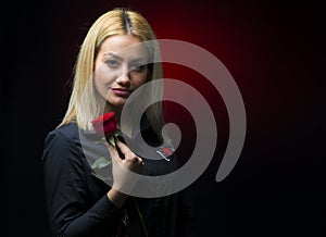 Portrait of a beautiful blonde girl with a red rose in her hand isolated