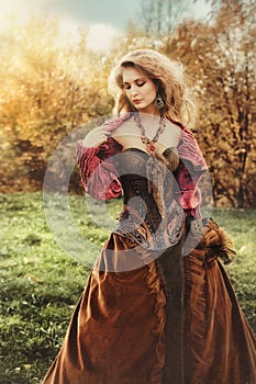 Portrait of a beautiful blonde woman in a historical costume in nature, photo