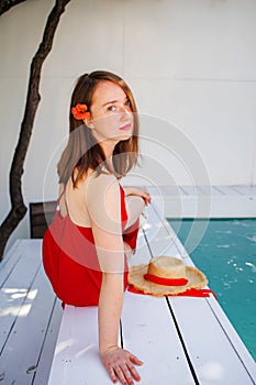 Portrait of a beautiful blonde woman outdoor near swimming pool wearing a red dress