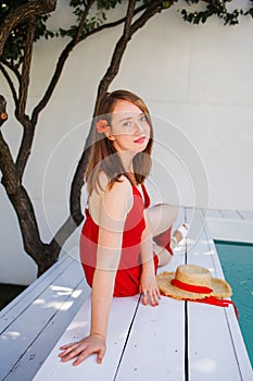 Portrait of a beautiful blonde woman outdoor near swimming pool wearing a red dress