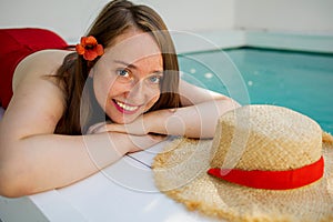 Portrait of a beautiful blonde woman outdoor near swimming pool wearing a red dress