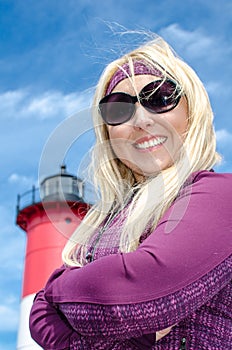 Portrait of a beautiful blonde woman, smiling with her arms crossed in front of Nauset Lighthouse on Cape Cod