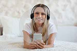 Portrait of beautiful blonde woman using headset and smartphone