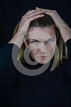 portrait of a beautiful blonde woman who with her hands on her head has a very determined and decisive look