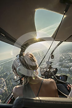 Portrait of beautiful blonde women enjoying helicopter flight. She is amazed by cityscape