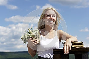 Portrait of a beautiful blonde young girl in the spring. Young woman holding bouquet of wildflowers in the nature