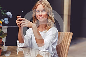 Portrait of beautiful blonde young woman in cafe with phone