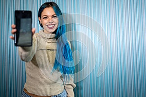 Portrait of a beautiful blue-haired hipster woman receiving a notification that causes her to have an extremely positive and photo