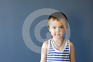 Portrait of a beautiful boy in a vest, smiling, isolated on a blue background