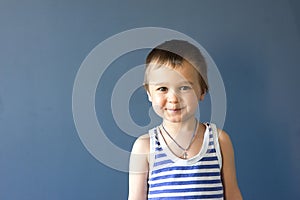 Portrait of a beautiful boy in a vest, smiling, isolated on a blue background