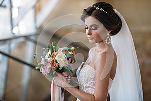 Portrait of beautiful bride with bouquet flowers in white luxury dress. Gorgeous model with bridal makeup and hairstyle
