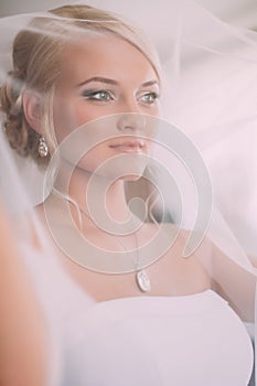 Portrait of beautiful bride with fashion veil posing at home at