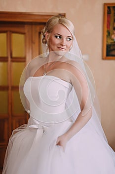 Portrait of beautiful bride with fashion veil posing at home at