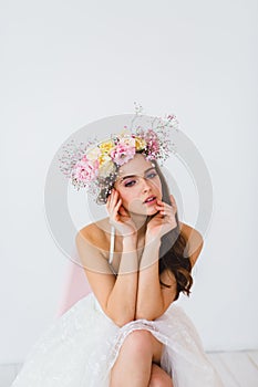Portrait of beautiful bride with flower wreath on her head at white background