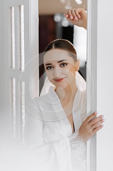 Portrait of a beautiful bride with stylish hair and makeup in a white robe posing looking into the lens