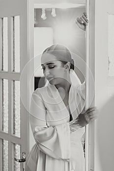 Portrait of a beautiful bride with stylish hair and makeup in a white robe posing looking into the lens