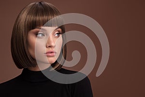 Portrait of a beautiful brown-haired woman with a short haircut on a brown background