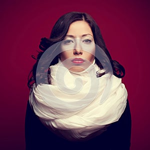 Portrait of a beautiful brunette with arty makeup wearing a vapory white silk scarf looking like cream