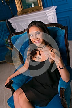 Portrait of a beautiful brunette in a black dress. Model posing in the interior