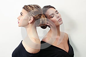 Portrait of beautiful brunette and blonde girls, in black with a cleavage on a light white background in a studio room, stars,