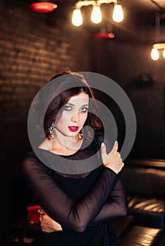 Portrait of a beautiful brunette girl in a black dress in a dark room 1