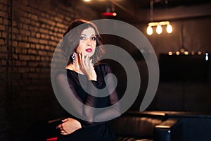 Portrait of a beautiful brunette girl in a black dress in a dark room 1