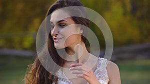 Portrait of beautiful brunette girl with long hair is posing in sunny rays at autumn park