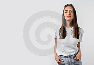 Portrait of beautiful brunette girl looking at camera suspiciously. Studio shot white background. Copy space