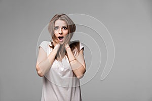 Portrait of beautiful brunette woman with a astonished expression posing in studio on gray background