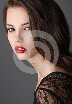 Portrait of beautiful brunette woman in black dress and red lips