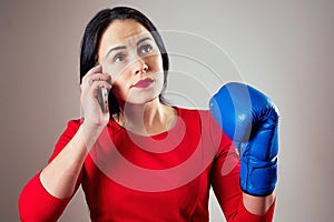 Portrait of a beautiful brunette woman with boxing gloves and a phone in her arms in the gym. athlete with makeup red