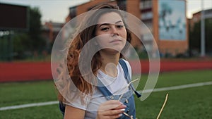 Portrait of Beautiful brunette woman inblue sundress sitting on the lawn near a football goal at the stadium. sunlight