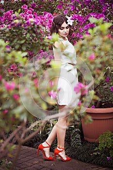 Portrait of a beautiful brunette woman in pink dress and colorful make up outdoors in azalea garden