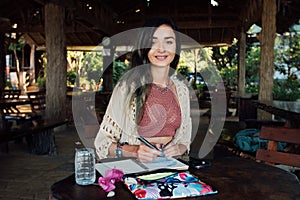 Portrait beautiful brunette woman smiling at wooden table in summer cafe