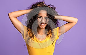 Portrait of beautiful brunette woman touching her natural curly hair and winking